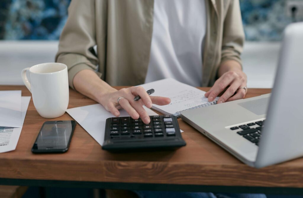 Pessoa usando planilha e calculadora para avaliar finanças antes de comprar imóvel