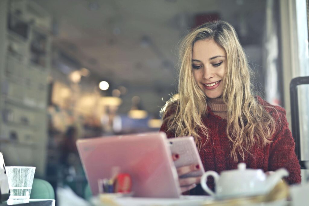Pessoa sorrindo e aliviada enquanto confere o controle financeiro no celular, representando organização com o cartão de crédito.
