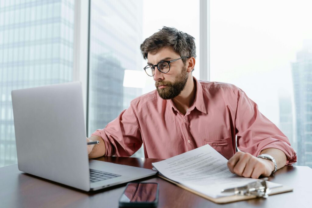 Homem organizando planilha de finanças pessoais no computador com expressão focada, representando disciplina e hábito de controle financeiro