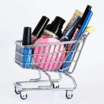 Mini carrinho de compras cheio de produtos de beleza acessíveis, simbolizando uma rotina de skincare e maquiagem econômica e inteligente.
